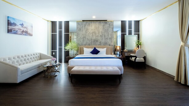 A modern hotel room with a large bed, a sofa, a desk, and a chair. - Sandals Star Hotel (Duc Trong)