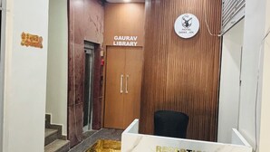 Una recepción con encimera de mármol y detalles dorados, un panel de pared de madera y un letrero para la Gaurav Library.
