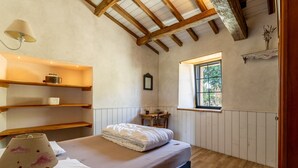 Ein Schlafzimmer mit Holzboden, einem Fenster, einem Bett, einer Lampe und Regalen.