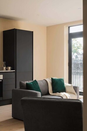 A modern living room with a sofa, a coffee table, and a black cabinet. - Bright Apartment Near Birmingham & Solihull (Birmingham)