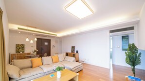 Ein modernes Wohnzimmer mit einer Couch, einem Couchtisch, Pendelleuchten und einer großen Pflanze.