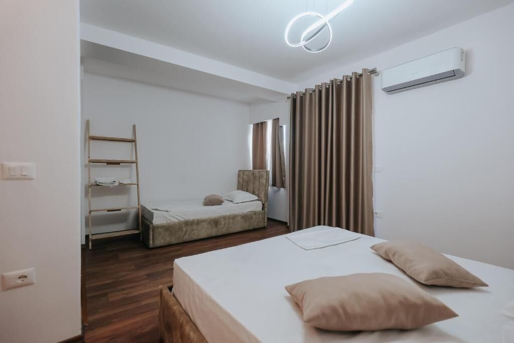 A bedroom with a bed, a small sofa, a ladder, and an air conditioning unit.