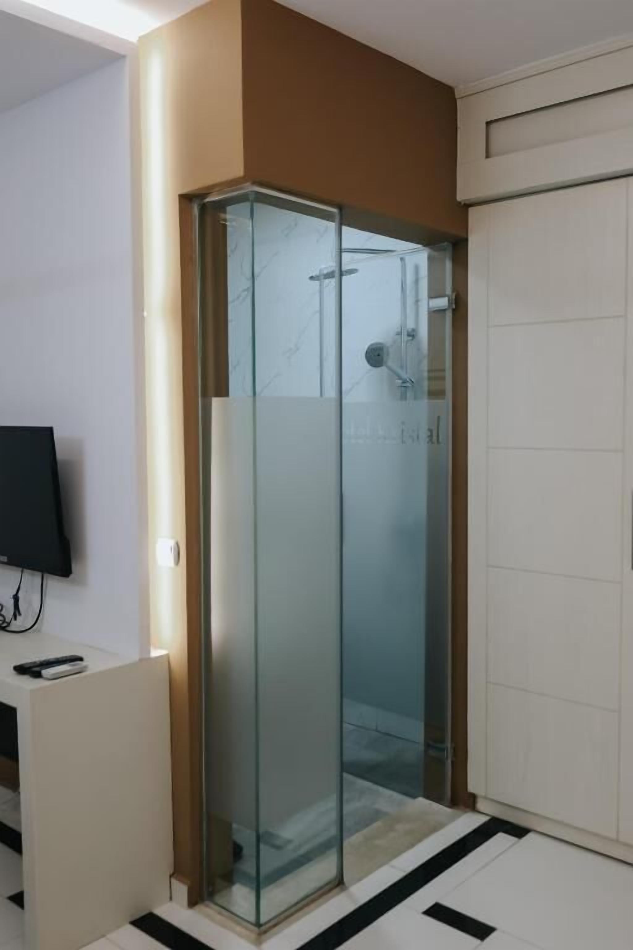 Un baño moderno con cabina de ducha de vidrio, radiador blanco y suelo de baldosas blanco y negro.