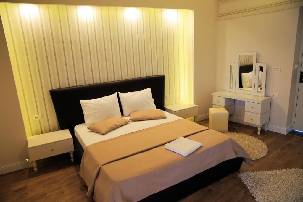 Une chambre à coucher comprenant un lit, des tables de chevet, une commode et un miroir.