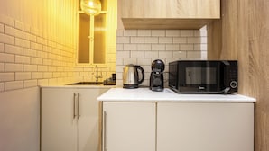 A compact kitchen with white cabinets, a microwave, a coffee maker, and a kettle. - Cozy 2BR Family-Friendly Pangrati (Athens)