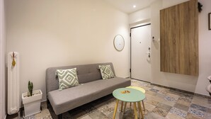 A modern living room with a grey sofa, two patterned cushions, a small round table, and a decorative plant. - Cozy 2BR Family-Friendly Pangrati (Athens)