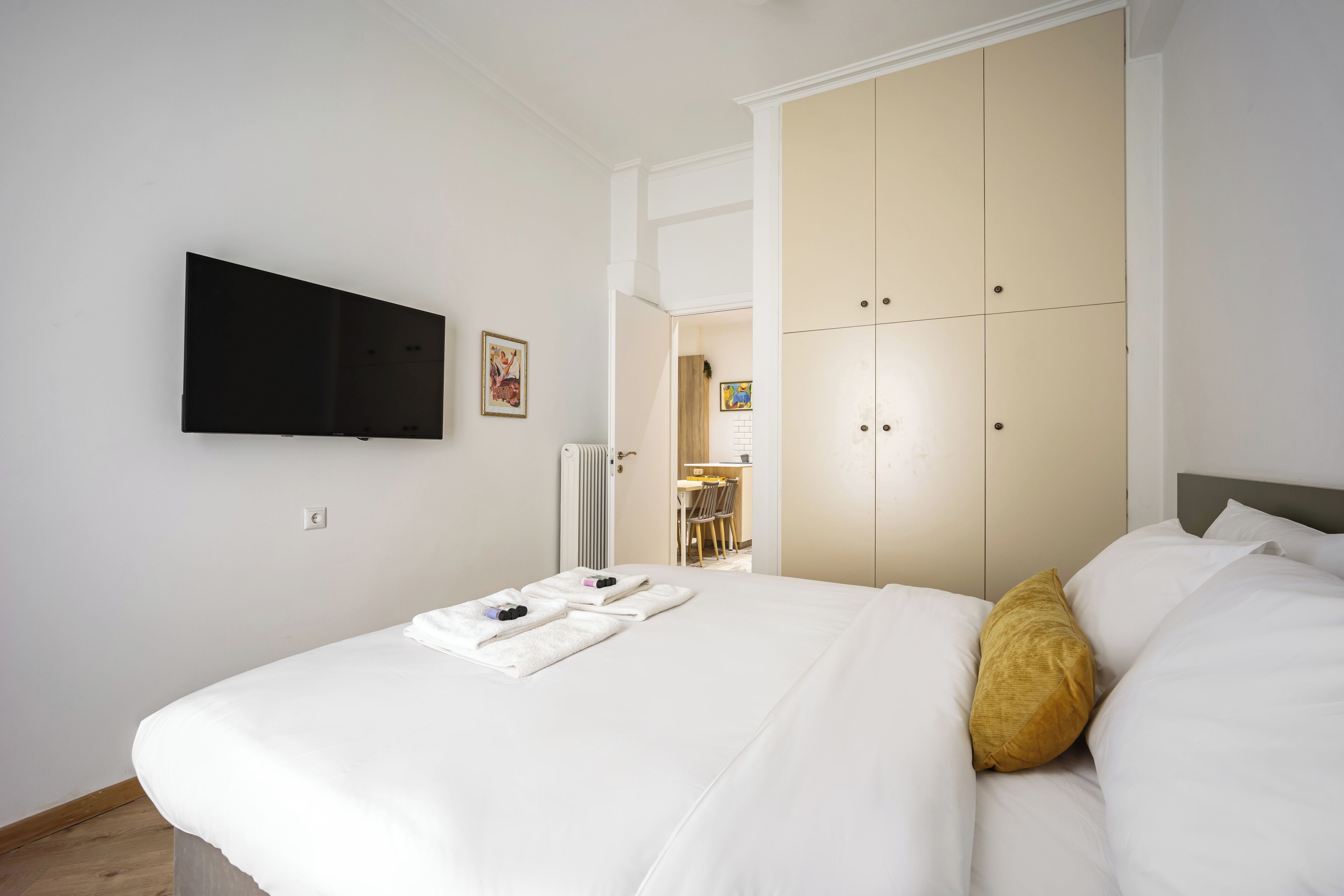 Ein Hotelzimmer mit einem Bett, einem an der Wand montierten Fernseher und einem Kleiderschrank.