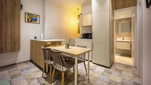 A compact kitchen with a dining area, featuring a wooden cabinet, a tiled backsplash, and a small dining table with chairs. - Cozy 2BR Family-Friendly Pangrati (Athens)