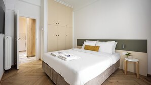 A neatly made bed with white linens and a small bedside table with a plant. - Cozy 2BR Family-Friendly Pangrati (Athens)
