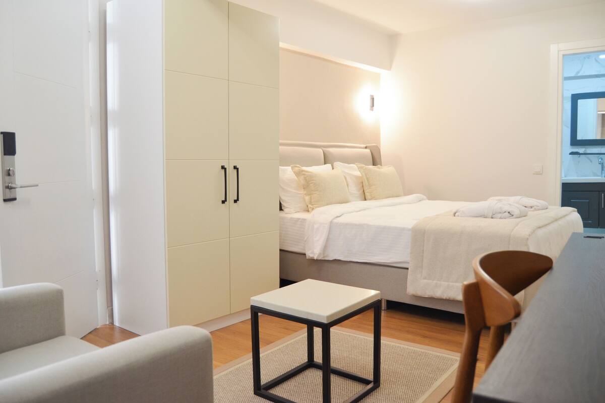 A modern bedroom with a bed, bedside table, and wardrobe.