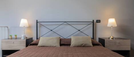A neatly made bed with a wooden headboard, two bedside tables with lamps, and a green throw blanket.