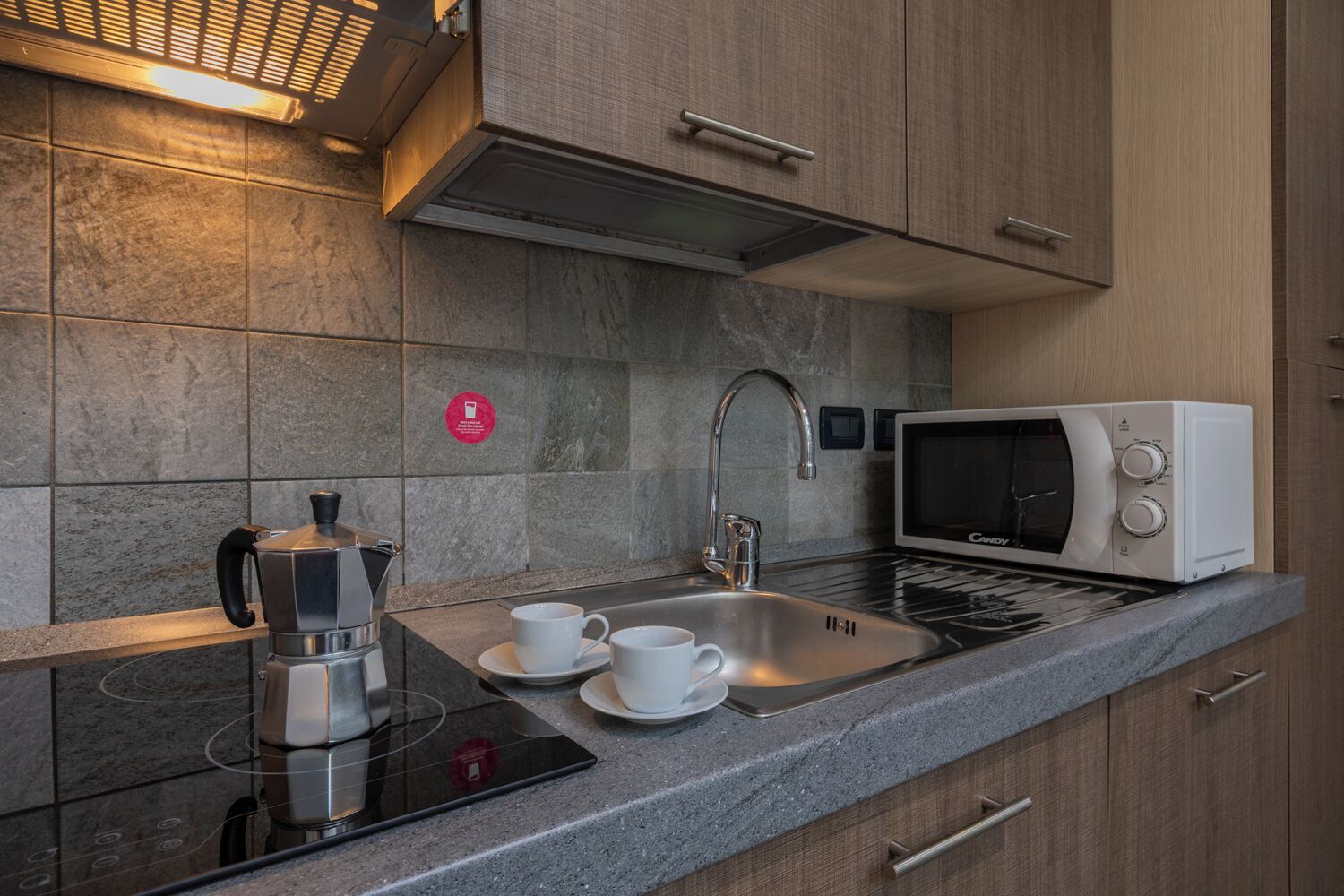 A modern kitchen with a built-in coffee maker, a microwave, and a sink.