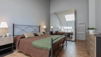 Un dormitorio moderno con cama, mesitas de noche, cómoda y espejo.