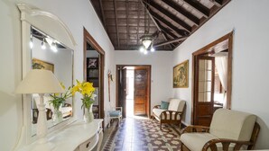 A room with a patterned floor, a white console table with a lamp, a mirror, and a wooden chair.