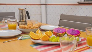 A breakfast table with croissants, dragon fruit, oranges, and a coffee pot.