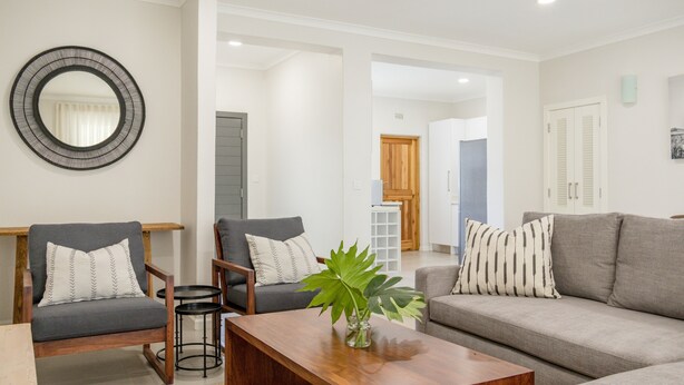 Una sala de estar con un sofá, dos sillones, una mesa de centro y un espejo.