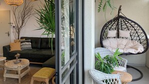 Ein modernes Wohnzimmer mit einem schwarzen Sofa, einem runden Holztisch und einem Hängekorbstuhl mit Kissen.