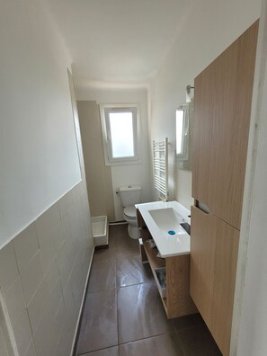 A small bathroom with a toilet, a window, a sink, and a mirror. - One-bedroom flat sleeps 4 seaside location, residence in Fabrégas, Les Sablettes (La Seyne-sur-Mer)