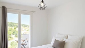 A bedroom with a large bed, a balcony with a table and chairs, and a ceiling light fixture. - One-bedroom flat sleeps 4 seaside location, residence in Fabrégas, Les Sablettes (La Seyne-sur-Mer)