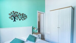Un dormitorio con cama, mesita de noche, armario y un adorno en la pared.