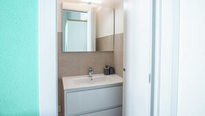 Un baño con un lavamanos blanco, un espejo y un armario.