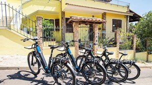 Un edificio amarillo con escaleras, un porche cubierto y bicicletas estacionadas al frente.