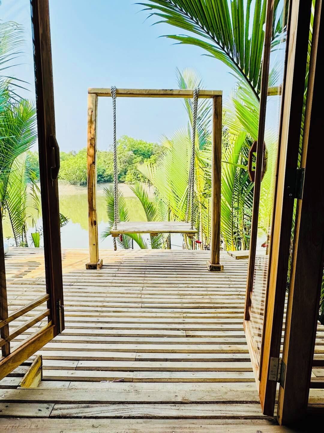 A wooden deck leading to a swing set with a view of a lush green landscape.