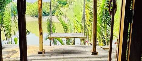 A wooden deck leading to a swing set with a view of a lush green landscape.