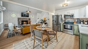 A modern kitchen with stainless steel appliances, a dining area with a round table and chairs, and a living room with a sofa and fireplace. - Poconos Pines Escape • Sauna • Hot Tub •Playground (Pocono Lake)