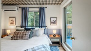 A bedroom with a bed, two bedside tables with lamps, a window with curtains, and a door to a balcony. - Poconos Pines Escape • Sauna • Hot Tub •Playground (Pocono Lake)