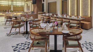 A modern dining area with wooden ceiling, round tables, and cushioned seating. - Regenta Anantam Resort Khatu Shyam Ji  (Danta Ramgarh)