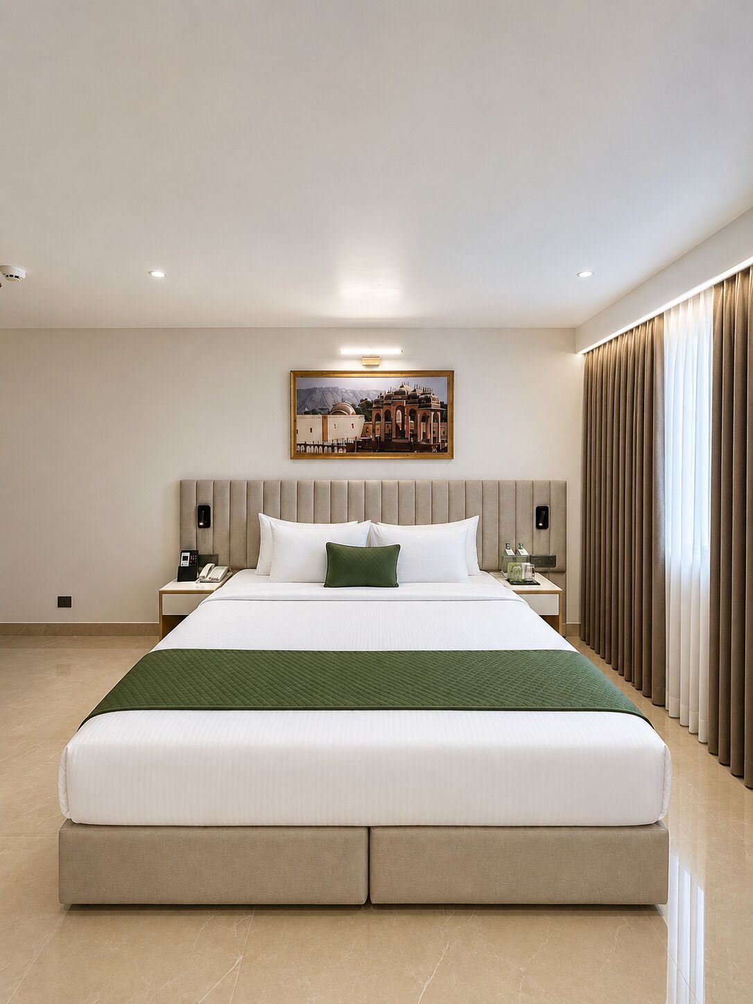 A hotel room with a large bed, a nightstand with a phone, a painting on the wall, and a window with curtains.