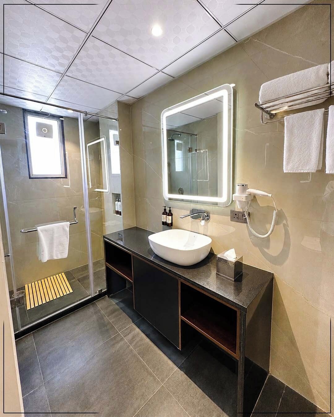 A modern bathroom with a glass-enclosed shower, a large mirror, and a vanity with a sink.