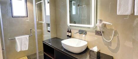 A modern bathroom with a glass-enclosed shower, a large mirror, and a vanity with a sink.