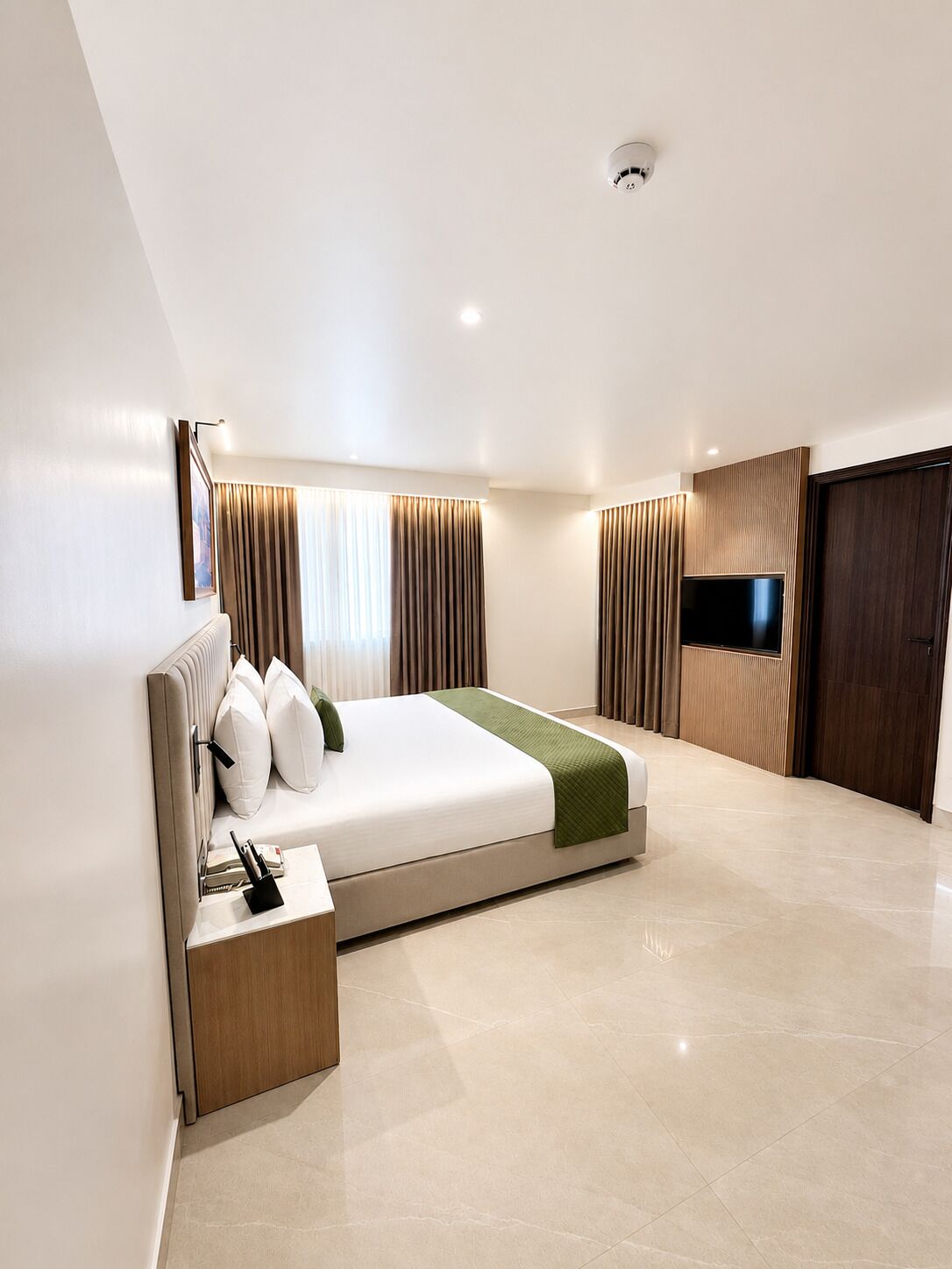 A modern bedroom with a large bed, a bedside table, a TV, and a wardrobe.