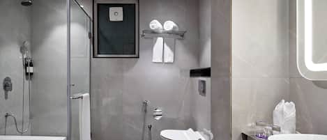 A modern bathroom with a glass-enclosed shower, a white toilet, and a large sink.