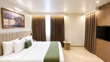 A modern hotel room with a large bed, a flat-screen TV, and a painting on the wall.