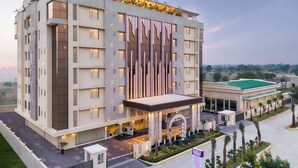A modern hotel with a prominent sign, multiple floors, and a well-lit entrance. - Regenta Anantam Resort Khatu Shyam Ji  (Danta Ramgarh)