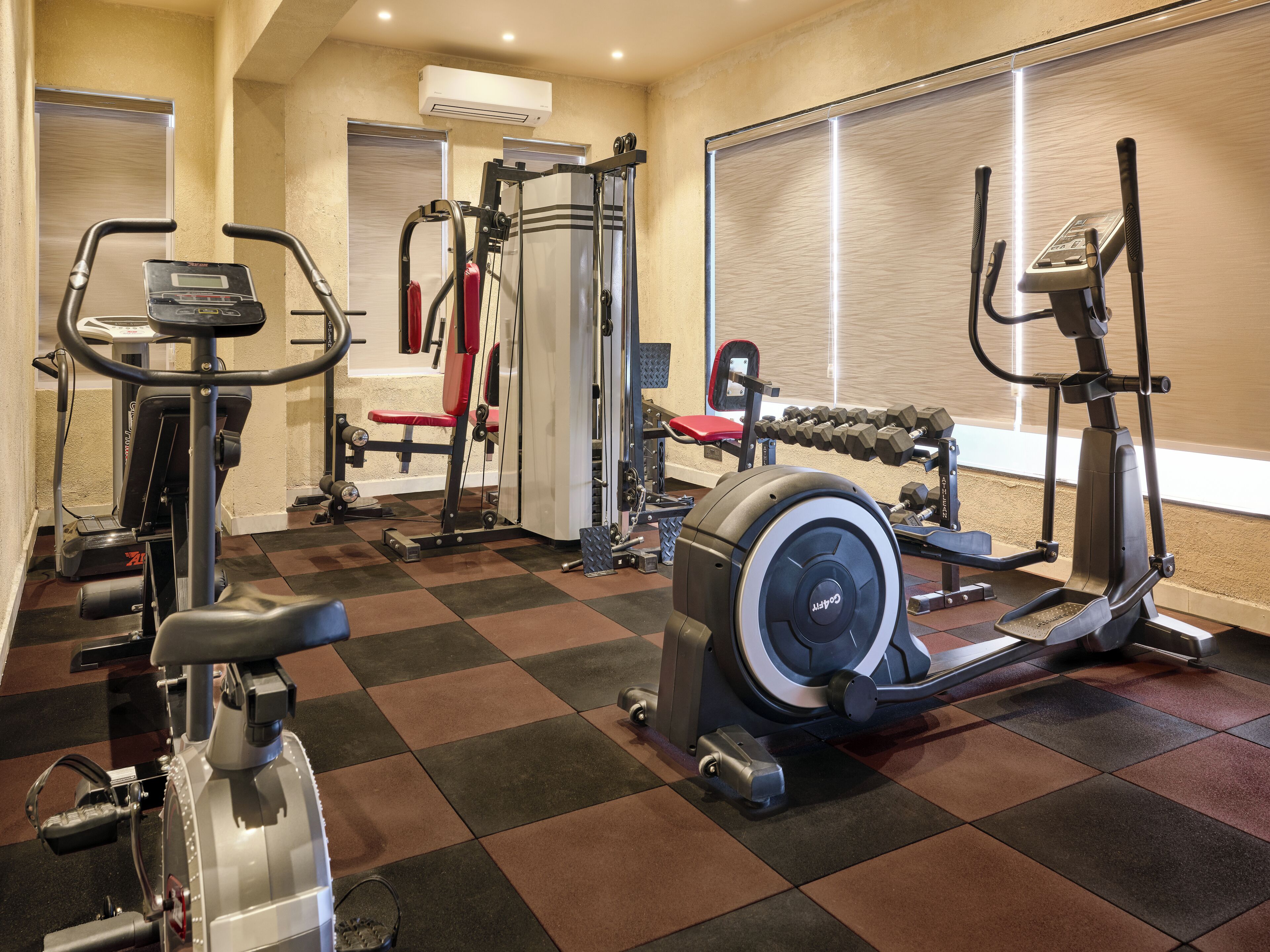 Un gimnasio con máquinas de cardio, equipo de levantamiento de pesas y una banca.