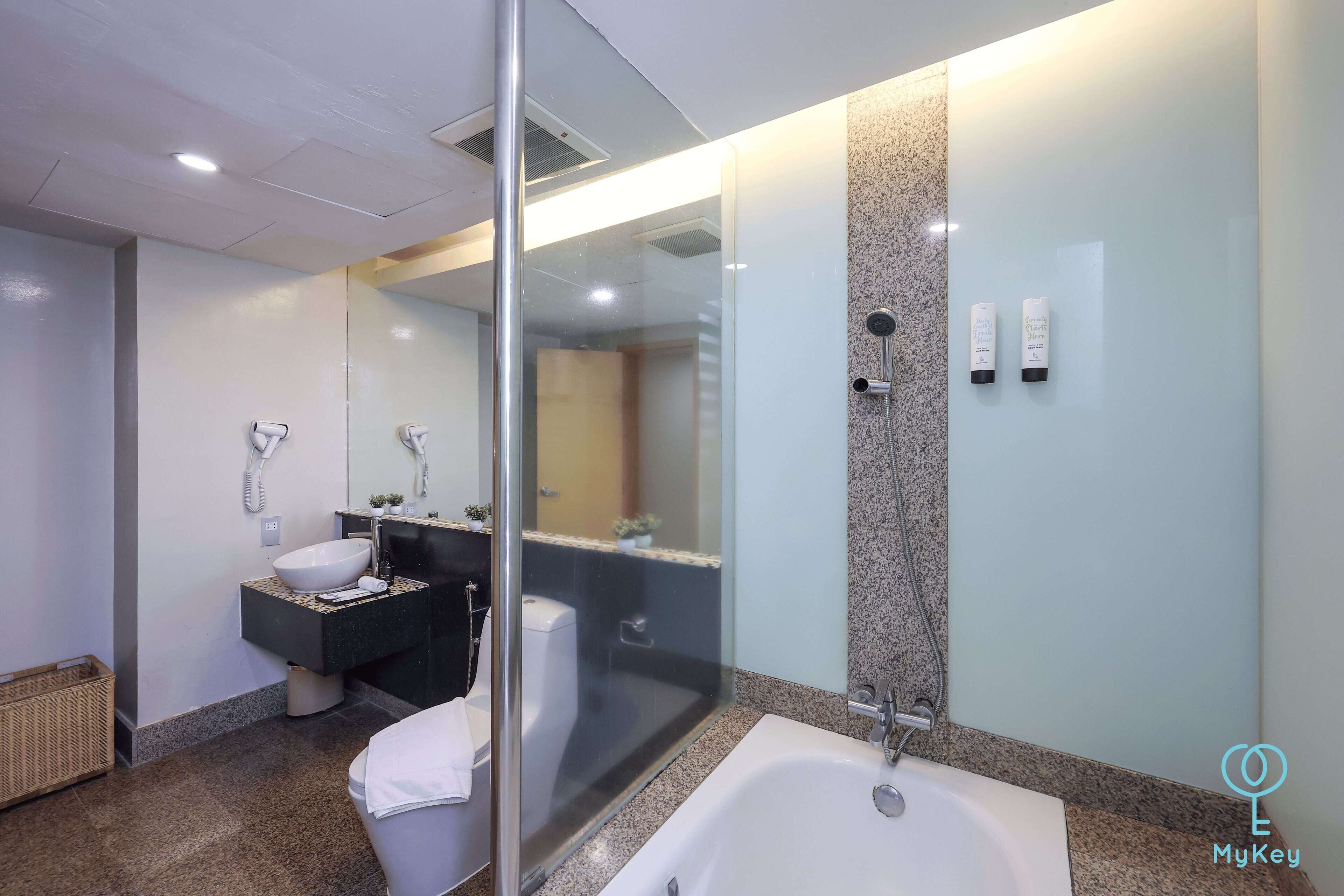 Een moderne badkamer met een douchecabine van glas, een witte badkuip en een wastafel met een wastafel en spiegel.