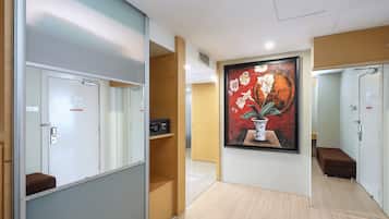 A hotel corridor with lockers, a painting, and a bench.
