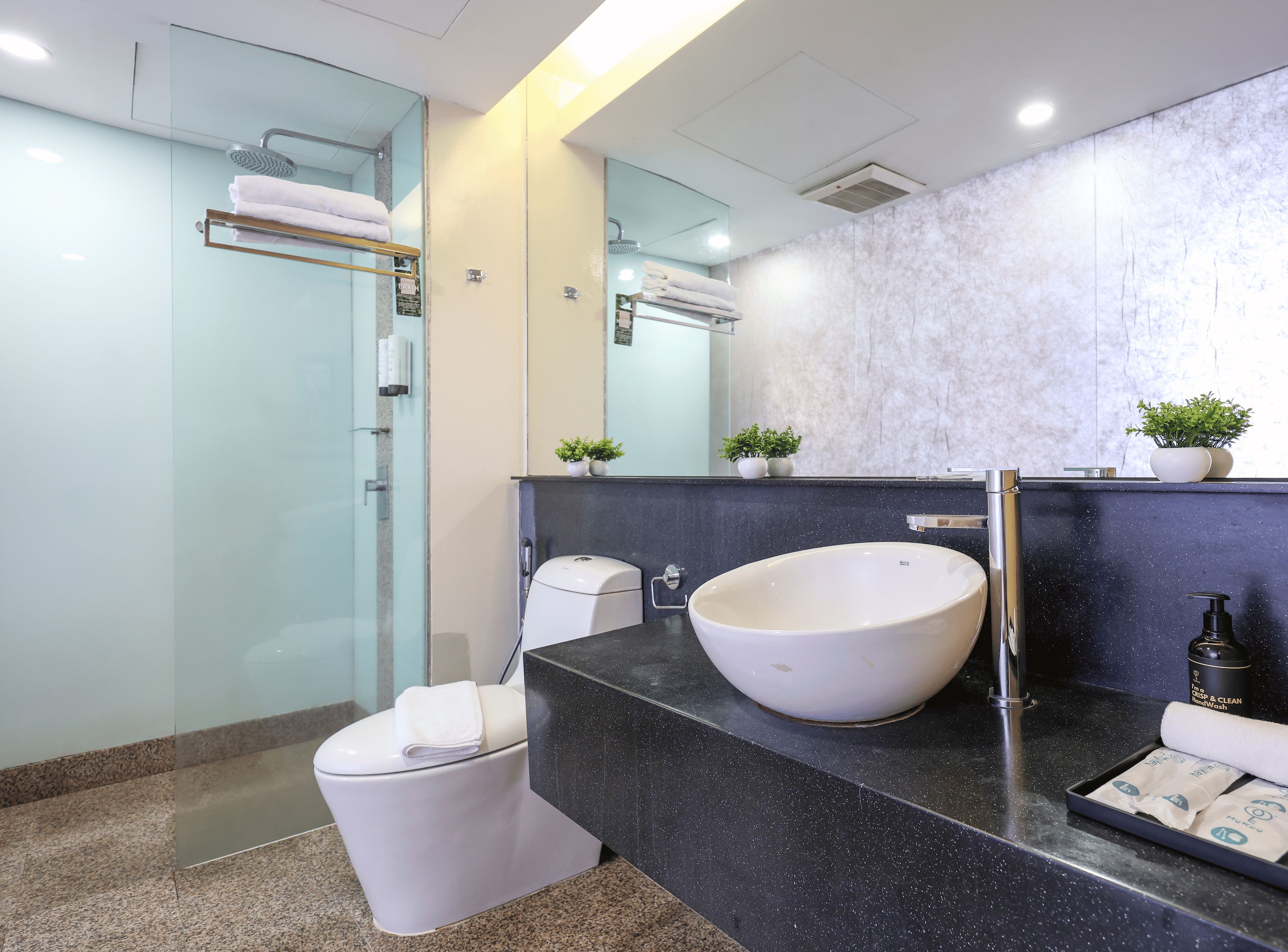 A modern bathroom with a large white sink, a glass shower enclosure, and a marble backsplash.