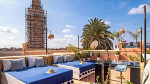 A rooftop terrace with two beds, a pool, and a palm tree. - Dar Alhambra Riad Medina (Marrakech)