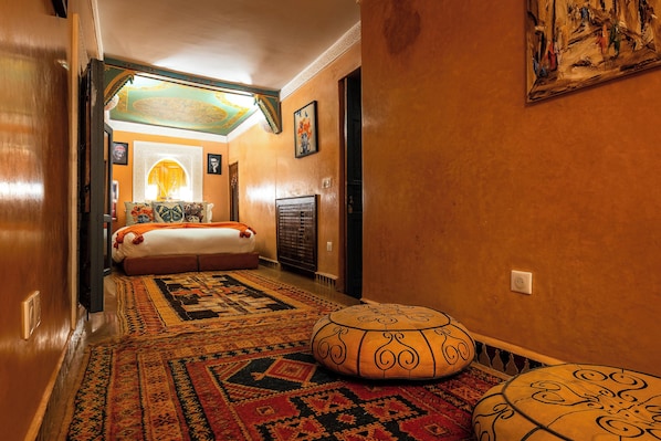 Un pasillo que conduce a un dormitorio con cama, radiador y alfombra estampada.