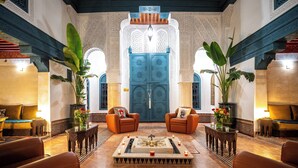 A lobby with a central fountain, two sofas, and a large blue door with intricate designs. - Dar Alhambra Riad Medina (Marrakech)