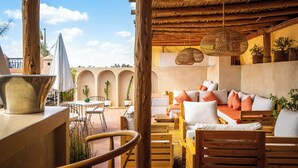 A cozy outdoor seating area with wooden furniture and a thatched ceiling. - Dar Alhambra Riad Medina (Marrakech)