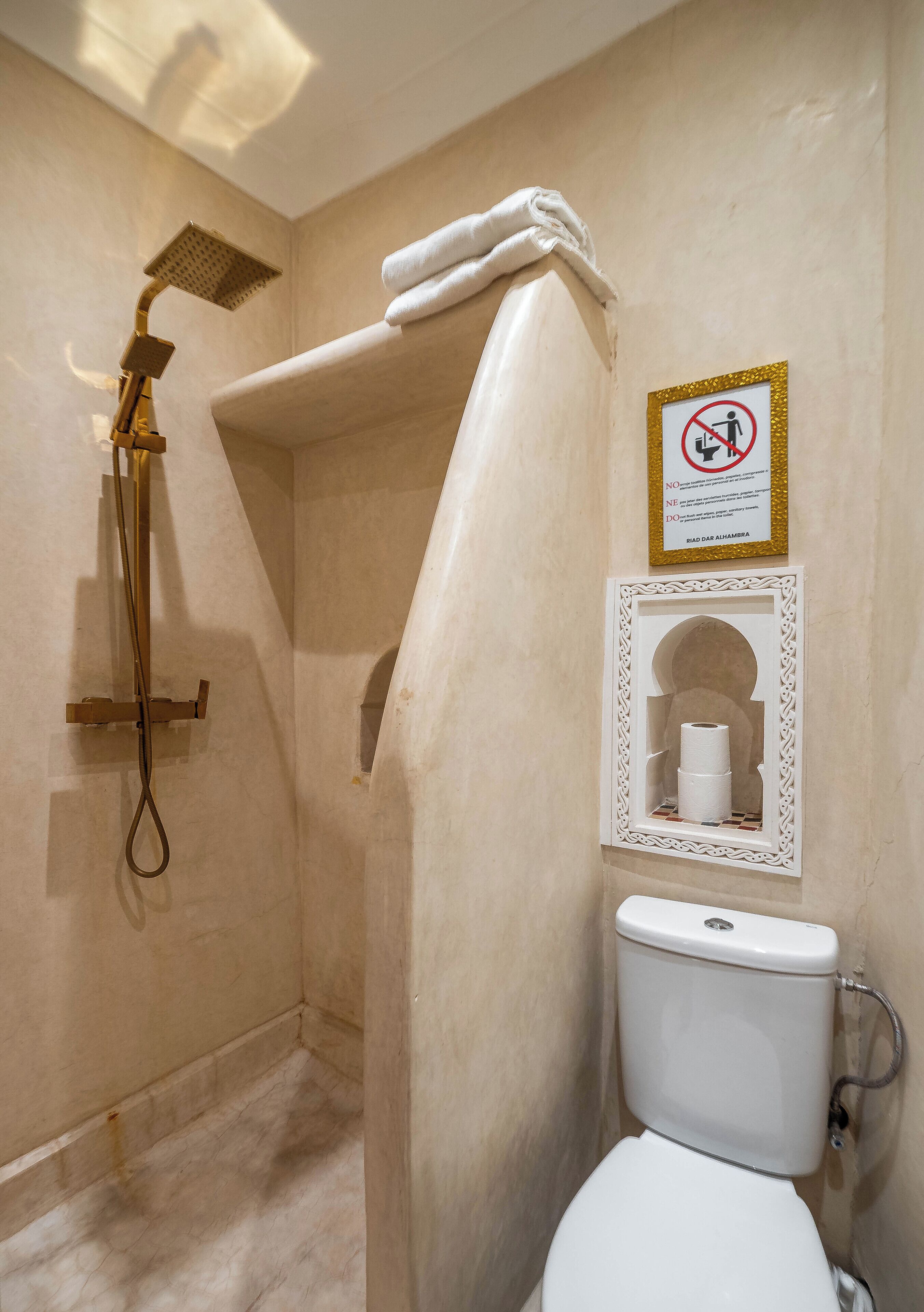 Un baño con ducha, inodoro y un cartel que indica que no se deben tirar toallas de papel al inodoro.