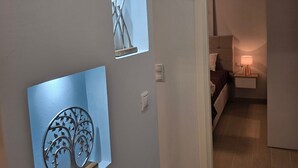 Ein Flur mit einem Bett, einem Nachttisch und einer Lampe im Hintergrund.
