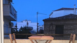 Ein Balkon mit zwei Holzstühlen und einem Tisch, Blick auf Gebäude, und bewölkter Himmel.