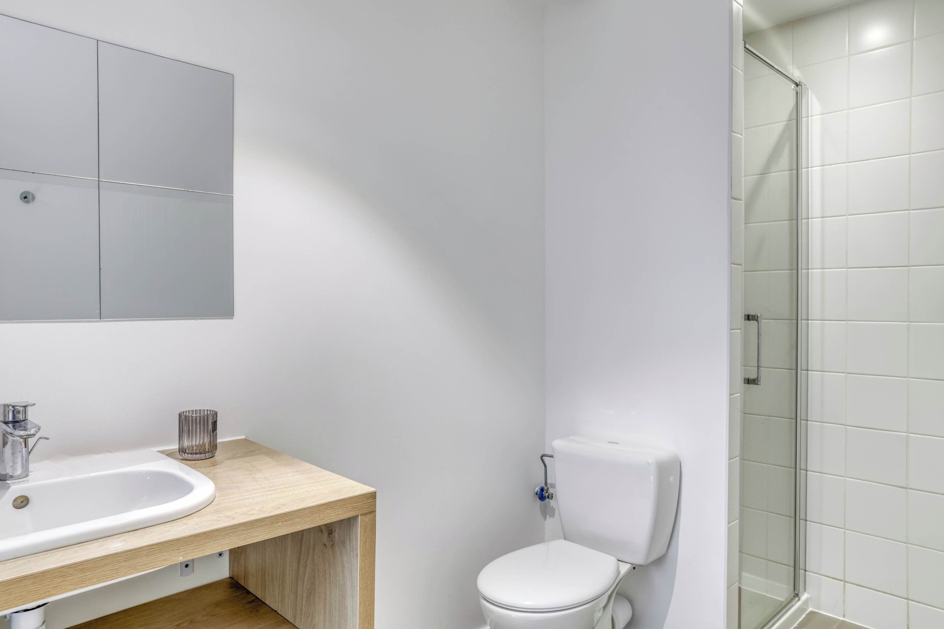 A modern bathroom with a sink, toilet, and glass shower enclosure.